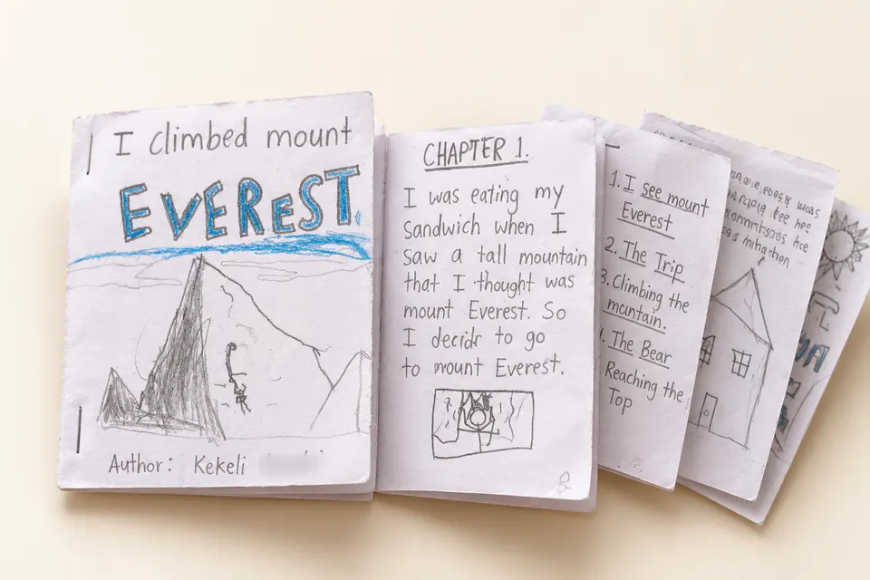 Kekeli's handmade storybook 'I Climbed Mount Everest', with a pencil drawing of a climber on a mountain on the cover, opened to Chapter 1 and the list of chapters.